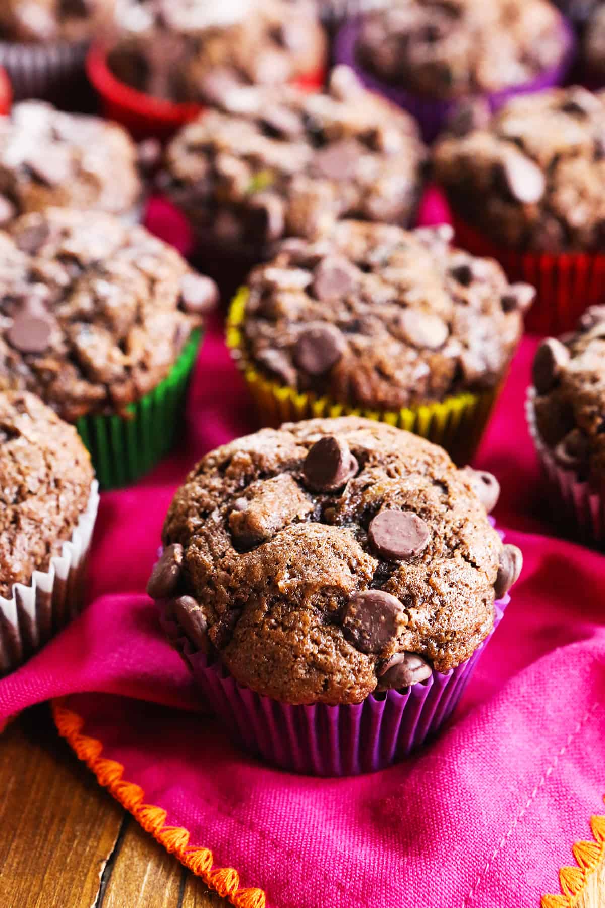 Double chocolate zucchini muffins lined up on a pink placemat.