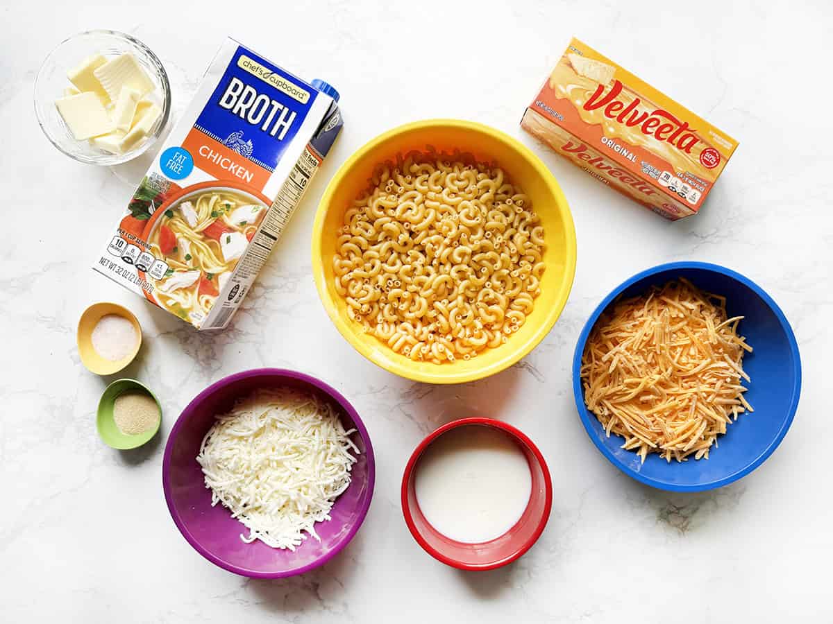 Recipe ingredients for macaroni and cheese lined up on a white counter.