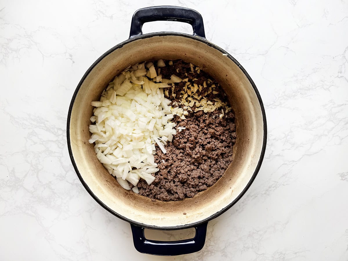 Ground beef, onions and garlic in a Dutch oven.