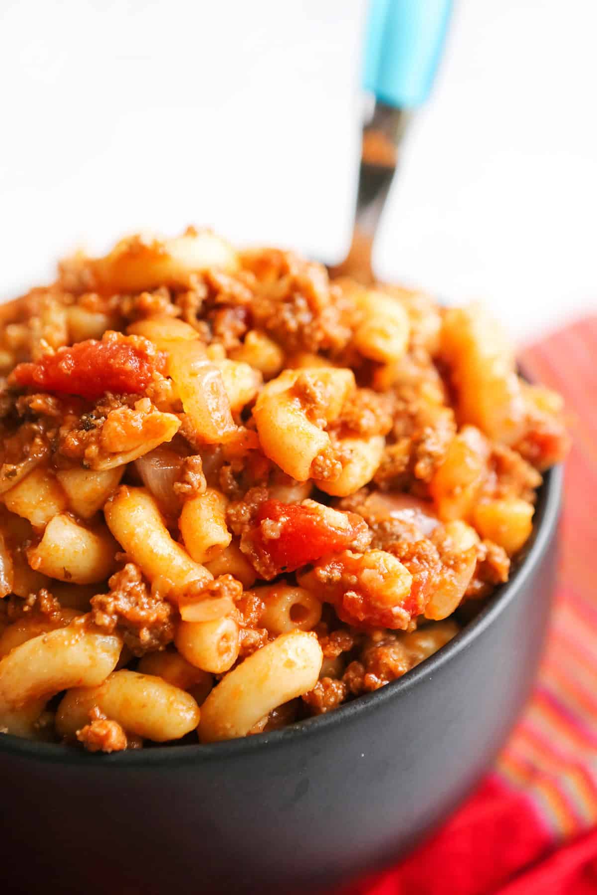 Hearty homemade beef and pasta chili in a black bowl with a spoon.