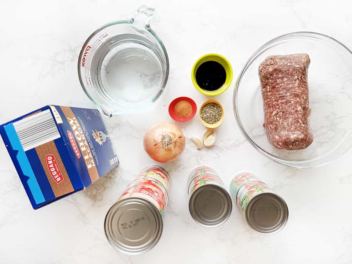 Raw ingredients for homemade meatloaf including ground beef, onion, spices, and canned goods.