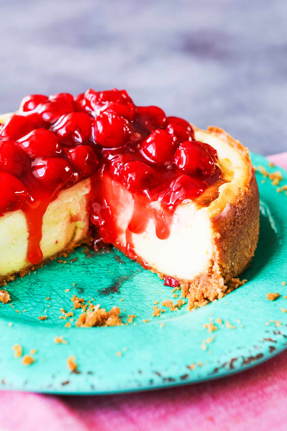 Cheesecake on a plate with cherries on top. 