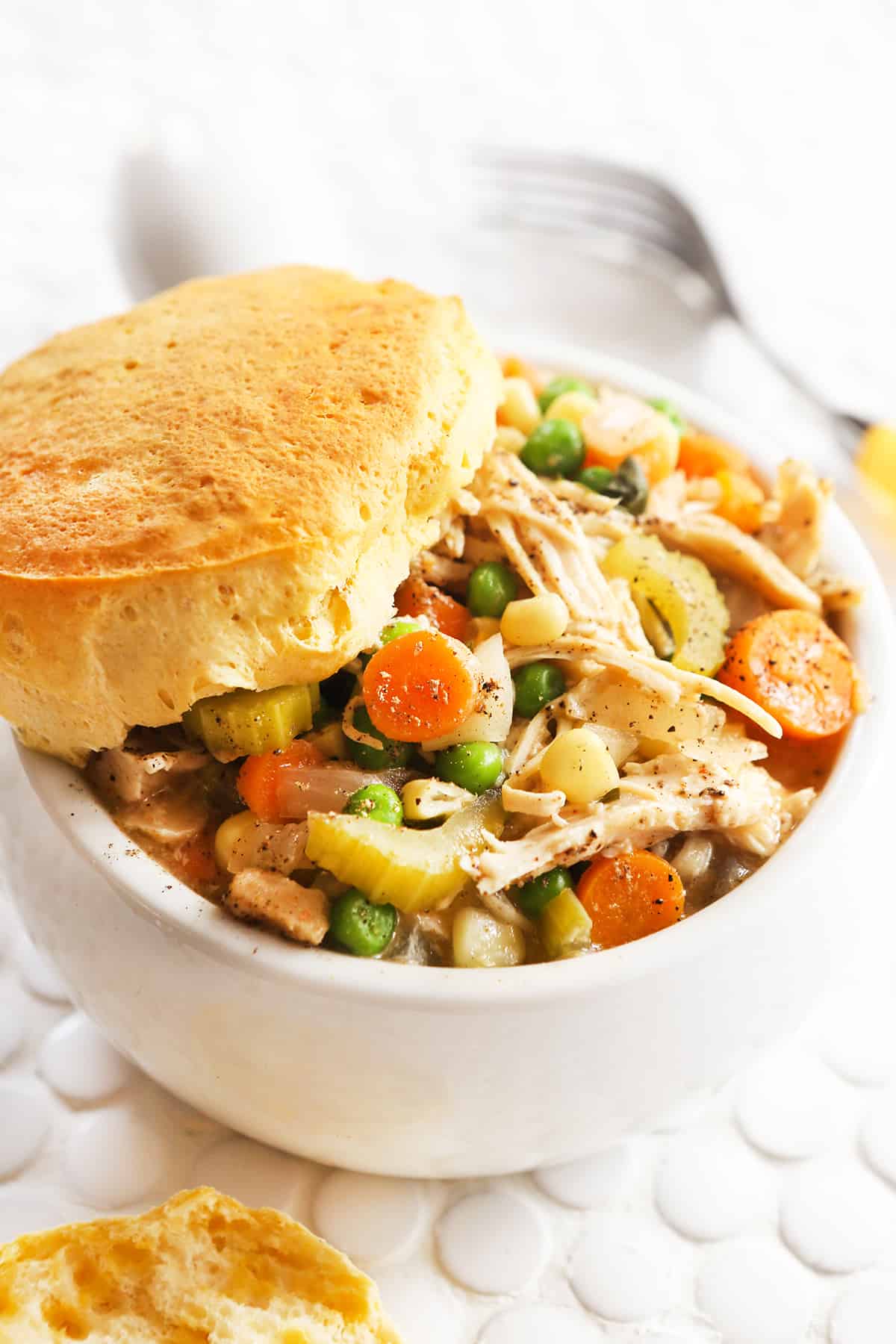 Chicken pot pie in a bowl with a biscuit on top. 