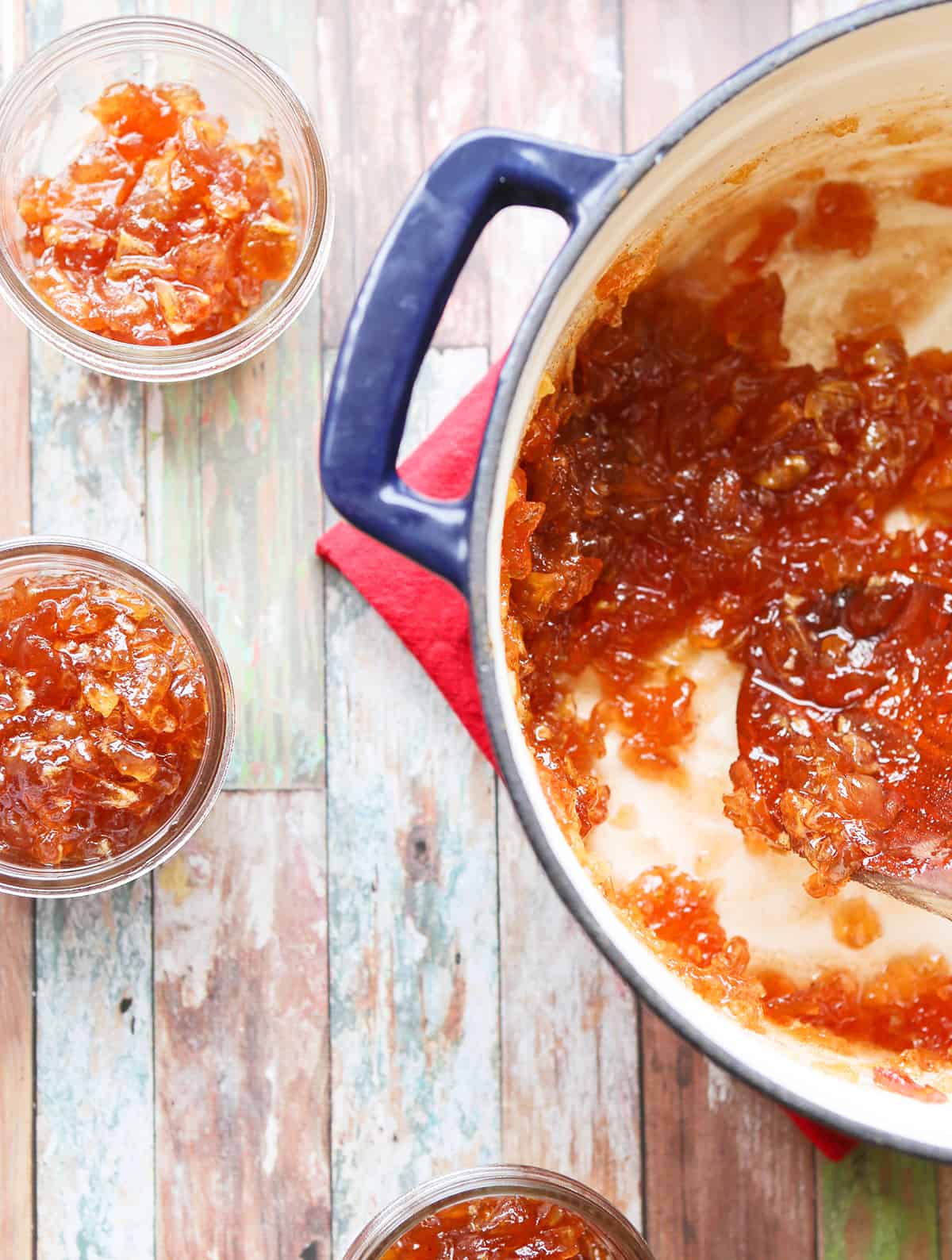 Top view of a saucepan filled with apple pie jam, sitting next to mason jars.