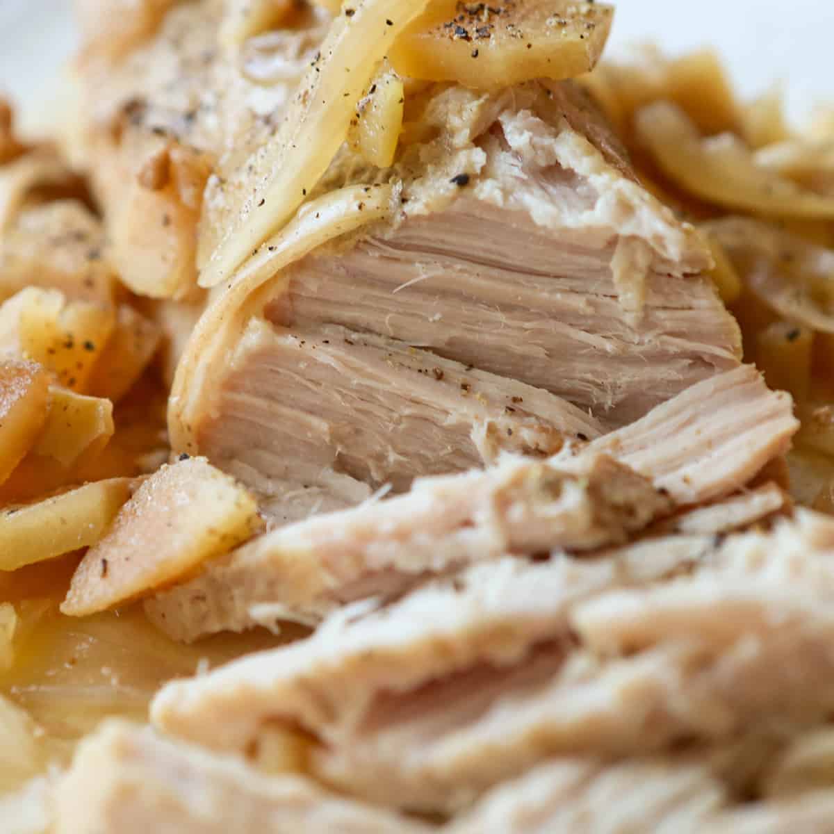 Close up of cooked pork with apples on top.