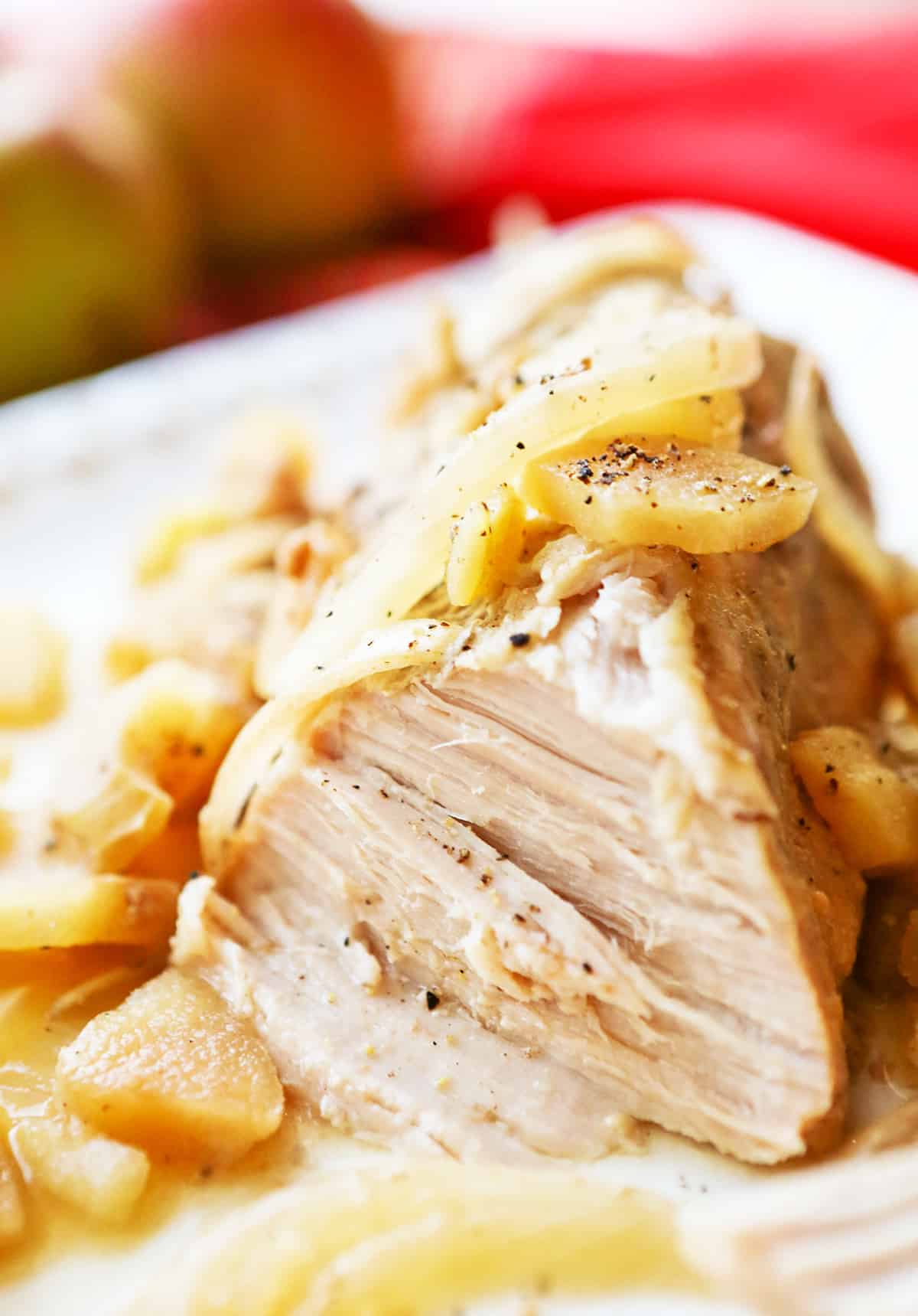 Pork tenderloin with juicy center meat exposed and cooked apples on top.