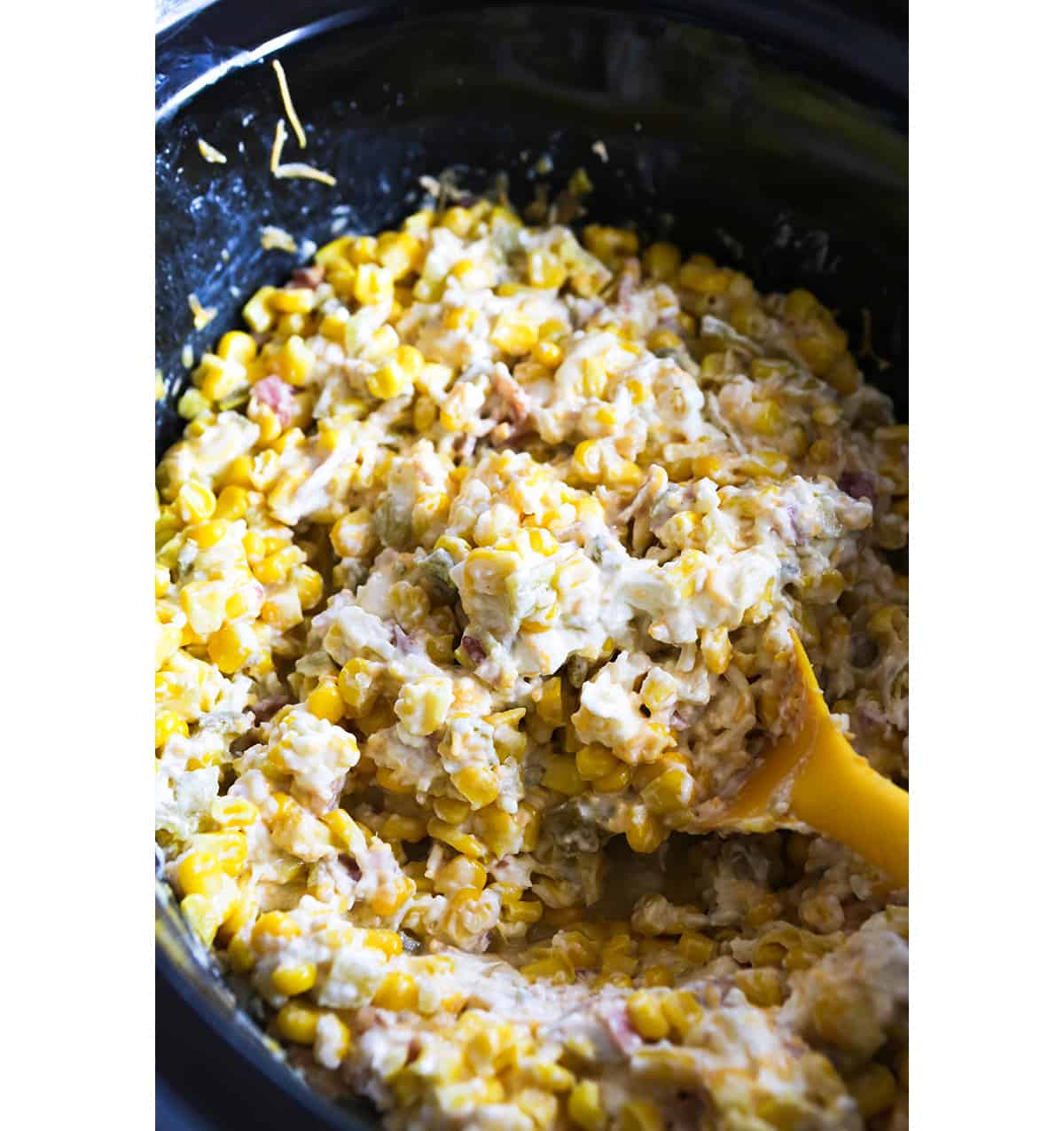 Spoon sticking out of a crockpot filled with corn dip.