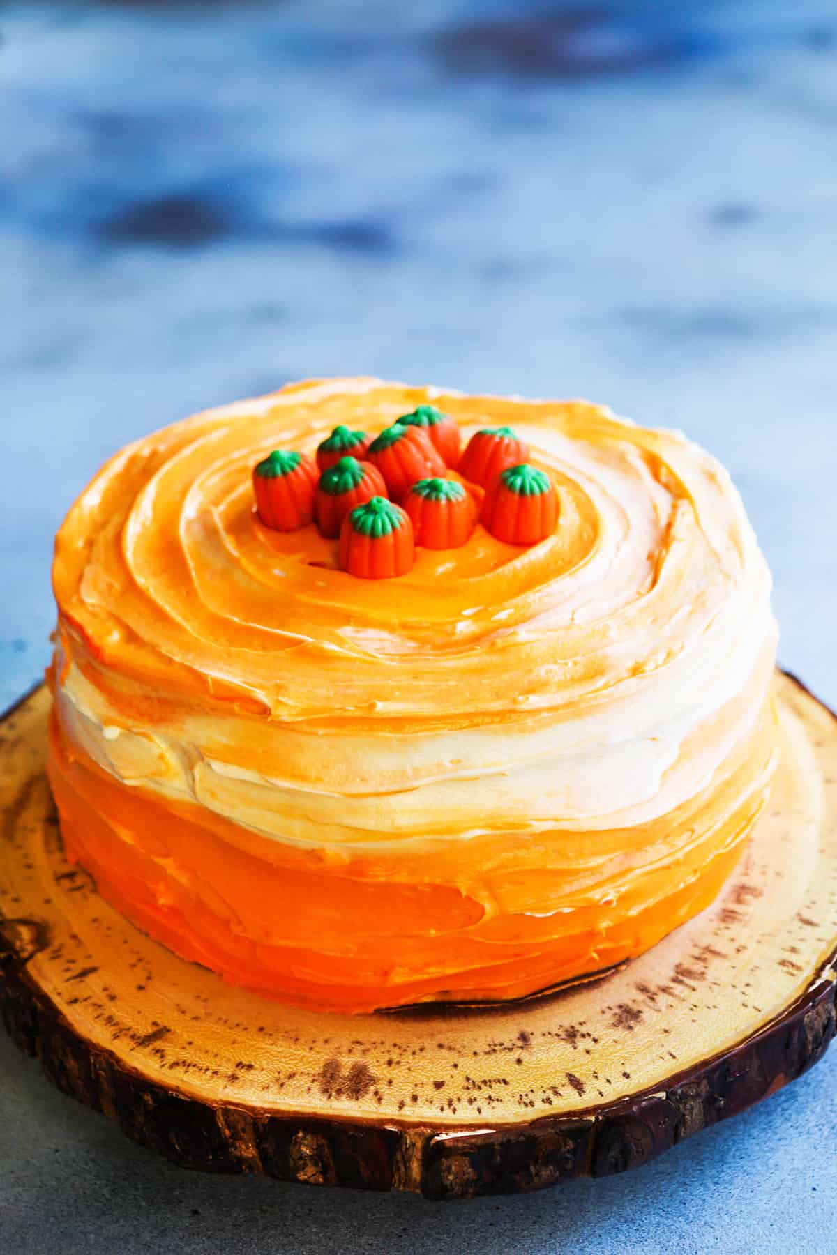 Beautiful pumpkin spice layer cake with ombre frosting and pumpkin candies on top.