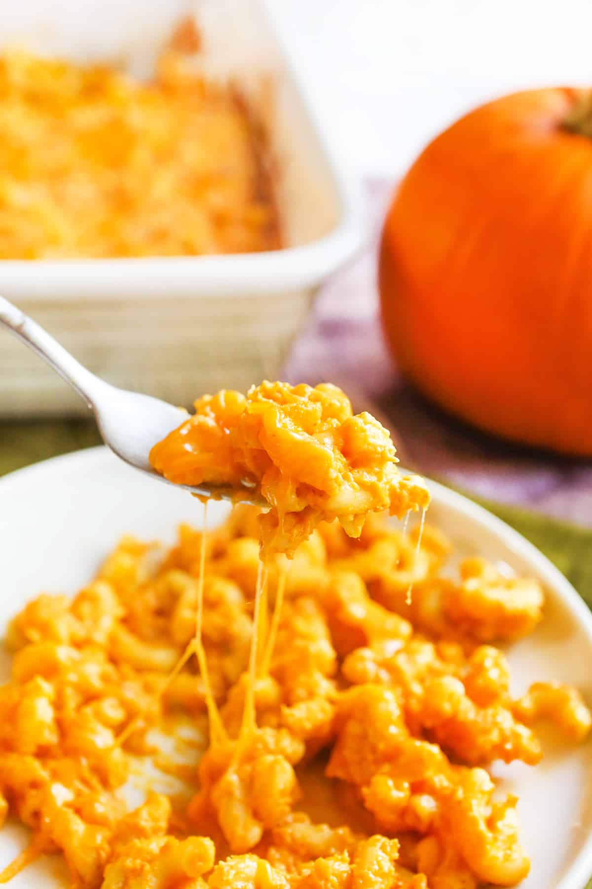 Forkful of gooey mac and cheese being pulled from a plate.