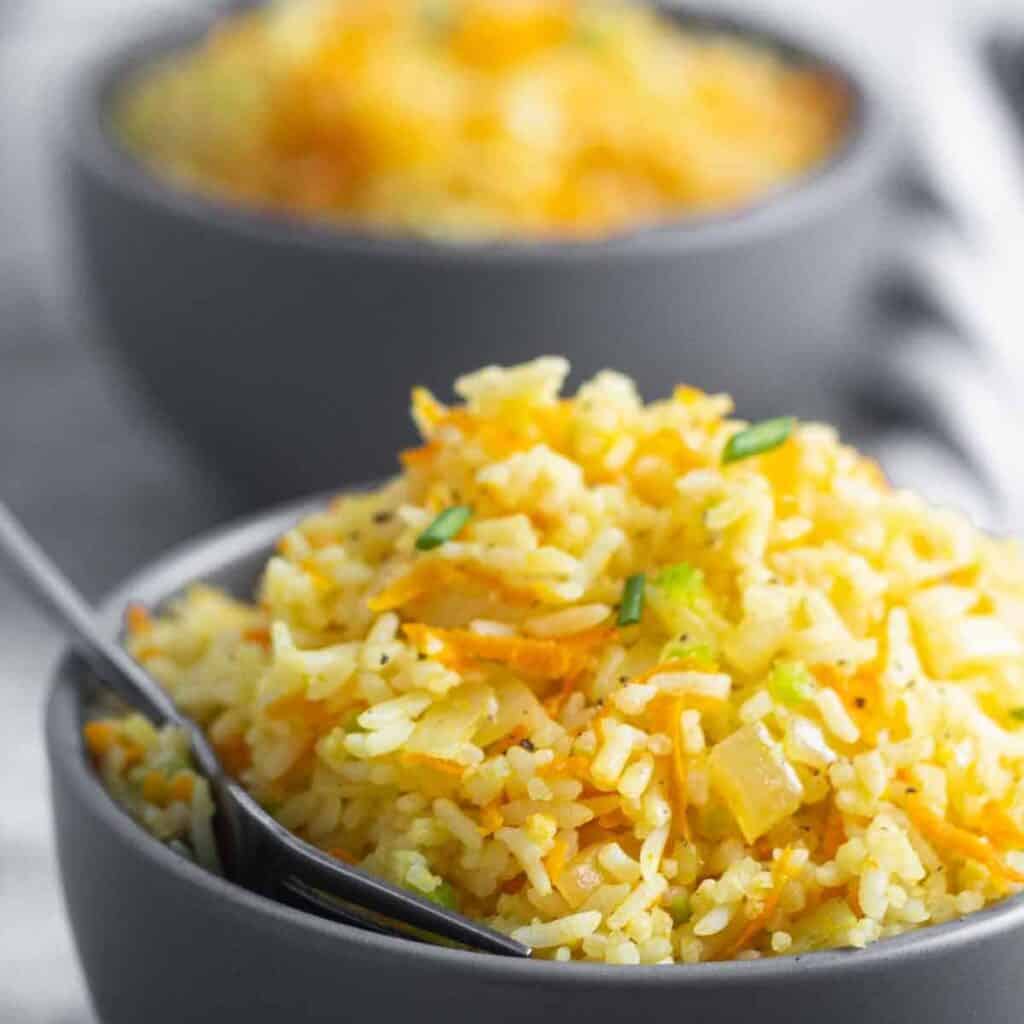 Bowl of rice and carrots with a spoon inside. 