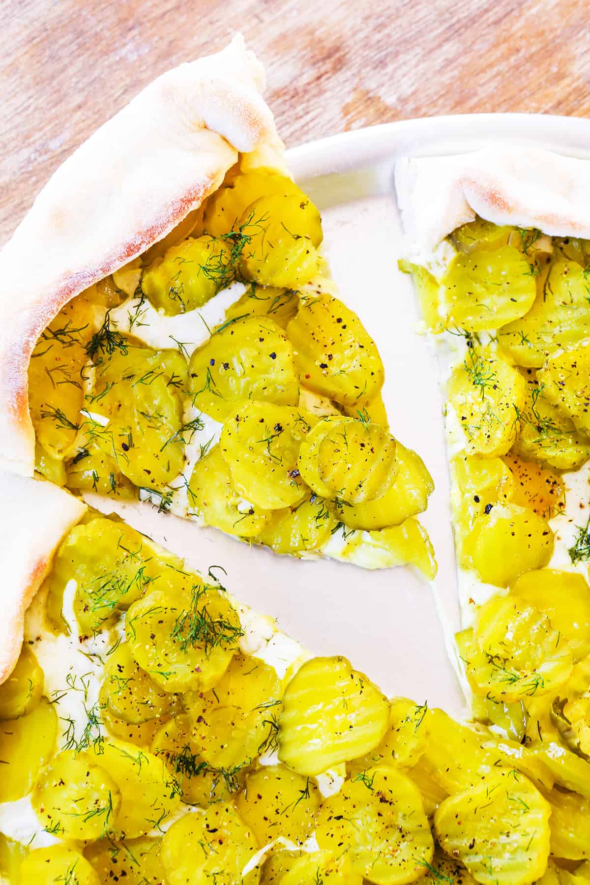 Pickle pizza with a slice cut out and sitting on a pan.