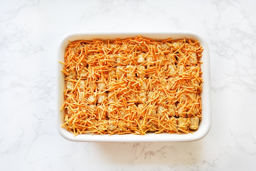 Baked cheesy chicken enchiladas with shredded cheese in a white dish.