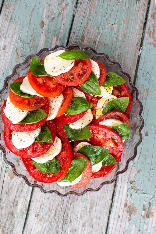 Caprese salad stacked on each other around the pie plate, sprinkled with olive oil, salt and pepper. 