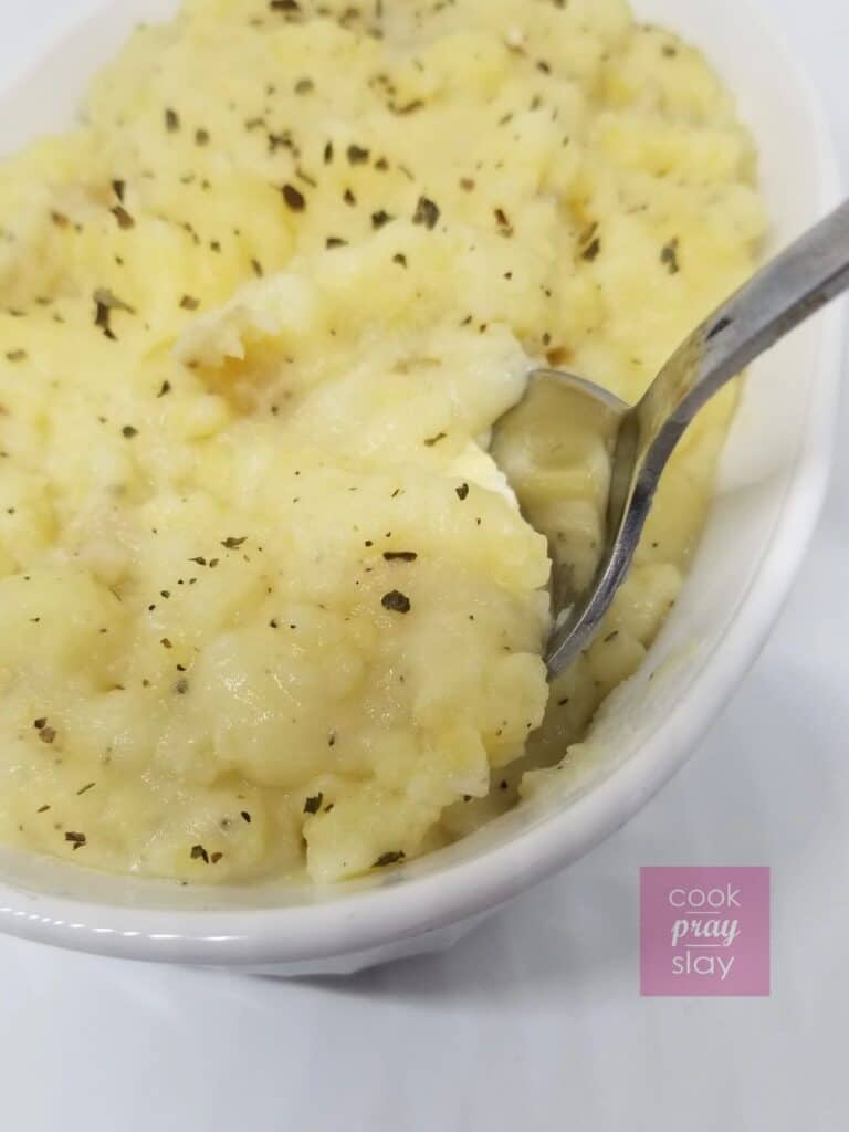 Spoon tucked into a bowl of mashed potatoes. 