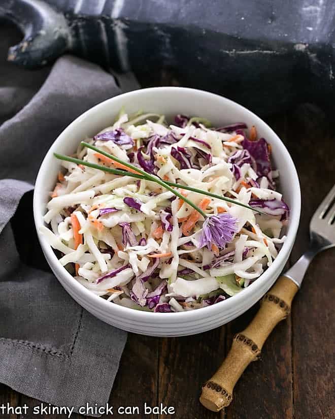A bowl of KFC cole slaw with buttermilk dressing and a fork sitting next to it. 