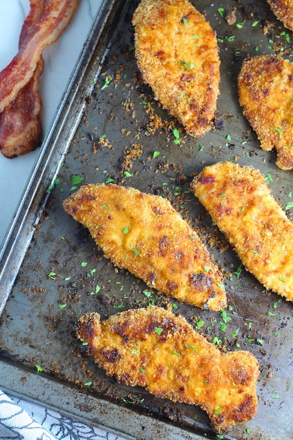 Jelly roll pan with chicken pieces baked topped with bacon crumbs and parsley.