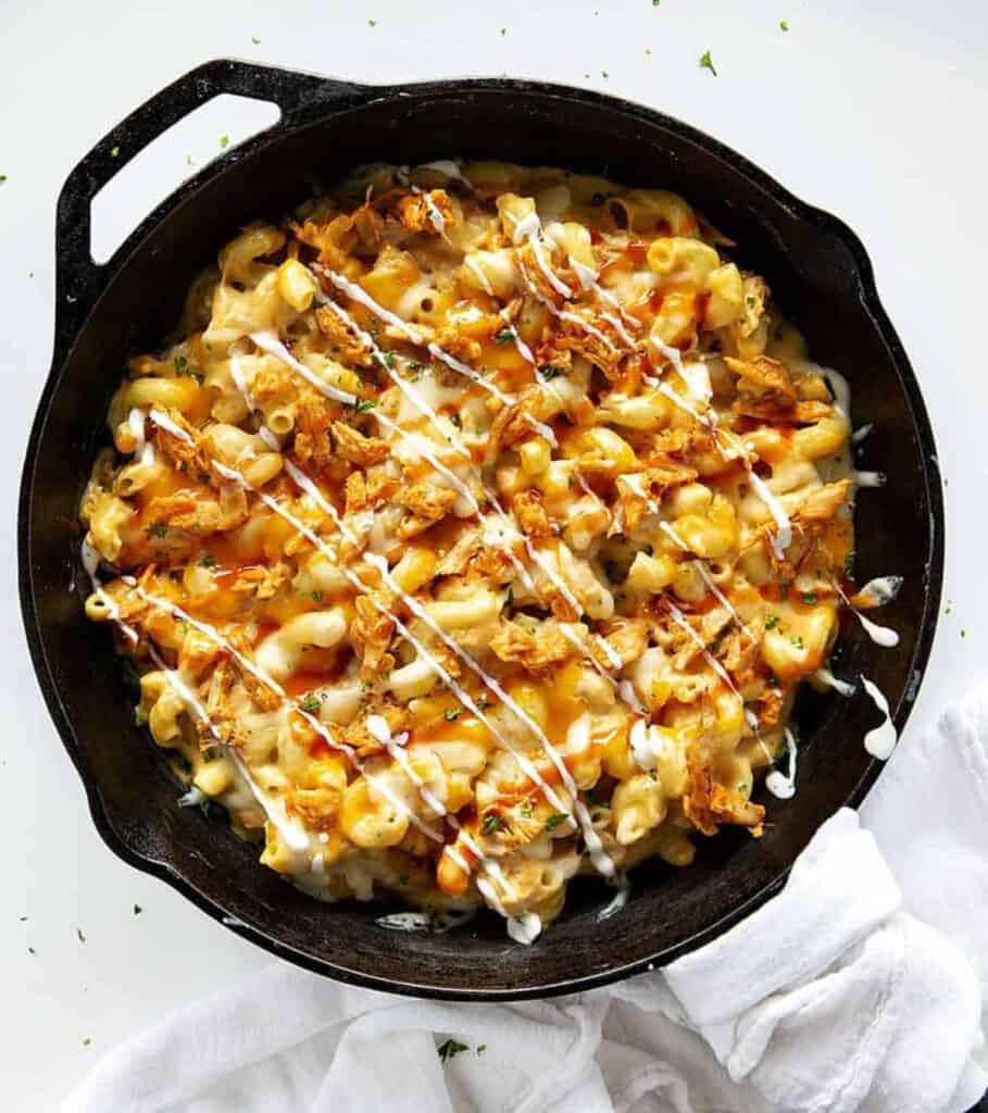 A cast iron skillet of prepared buffalo chicken mac and cheese. 