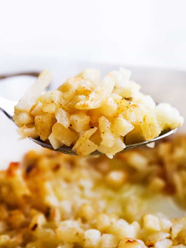 Hash brown casserole being scooped up on a serving spoon. 