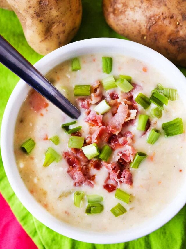 Looking down into a bowl of potato soup topped with bacon and green onions.