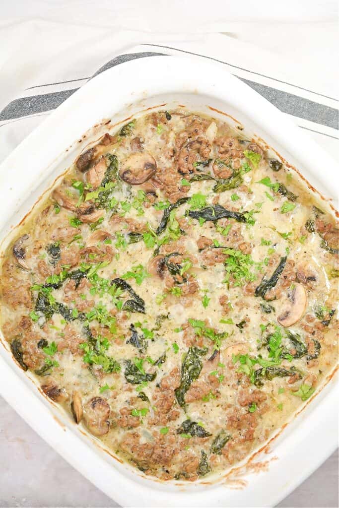 Ground beef casserole with mushrooms and spinach baked and ready to serve in a casserole dish. 