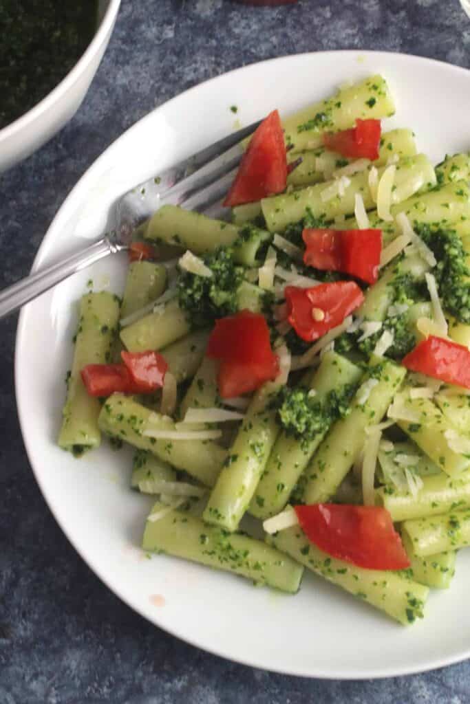 Kale pesto salad on a plate with a fork tucked into it. 