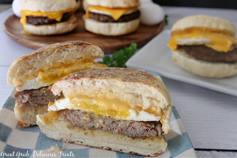 A sausage, egg and cheese biscuit sliced in a half, sitting on a plate ready to be enjoyed. 