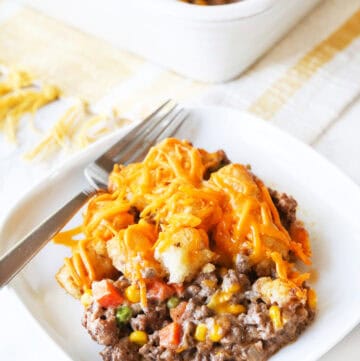 Delicious cheesy hotdish with ground beef, corn, and melted cheese on a white plate.