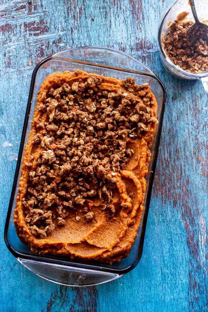 Casserole glass dish of sweet potato casserole with 2/3 covered in brown sugar topping and a section without. 