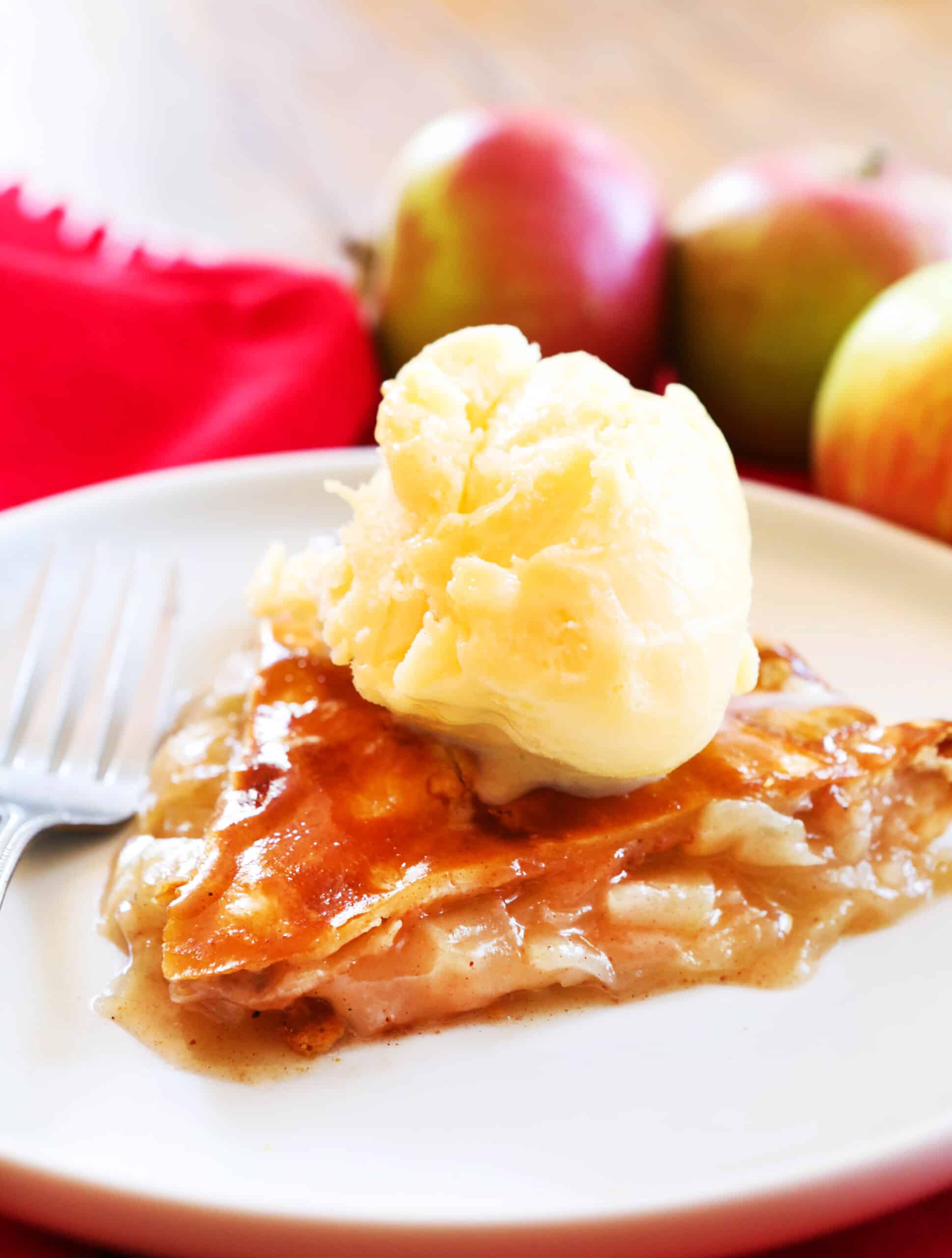 Slice of apple pie with a scoop of vanilla ice cream on top.