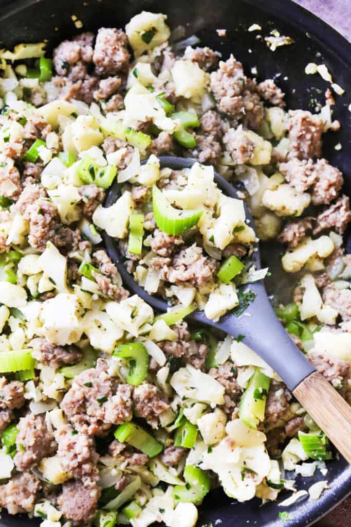 Cauliflower stuffing in a skillet with a spoon. 