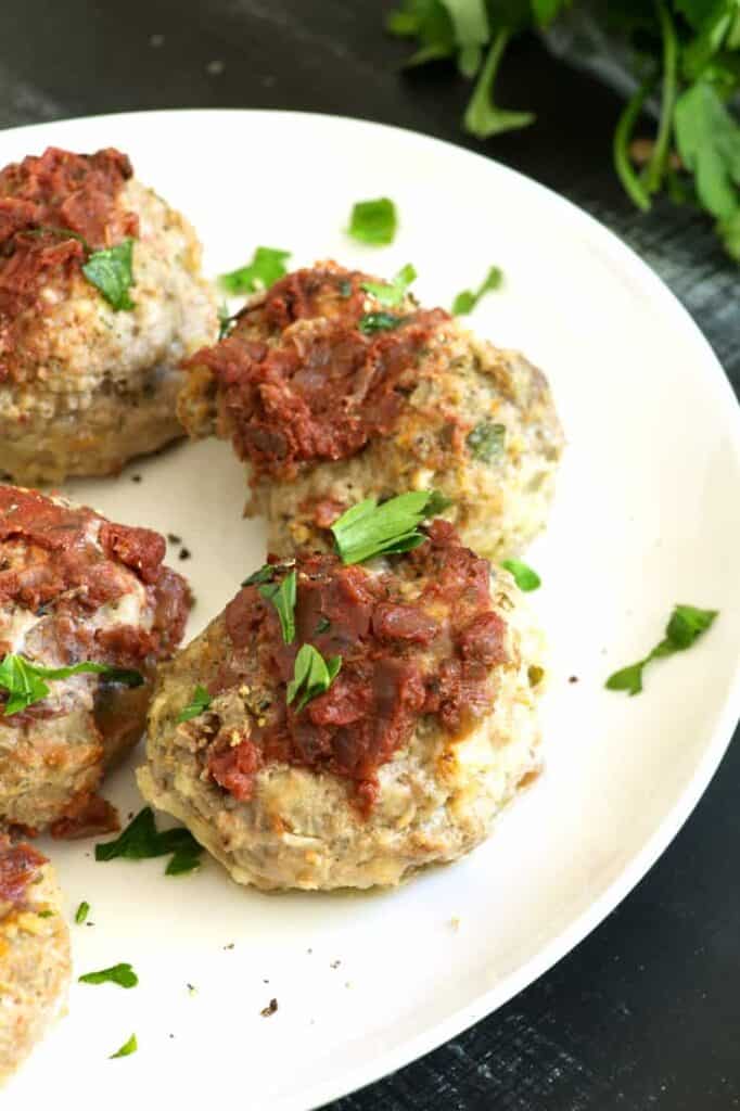 Mini meatloaf muffins sitting on a white plate. 