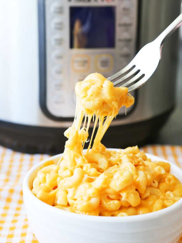 f=Fork pulling out a gooey bite of velveeta mac and cheese from a bowl, sitting in front of the instant pot. 