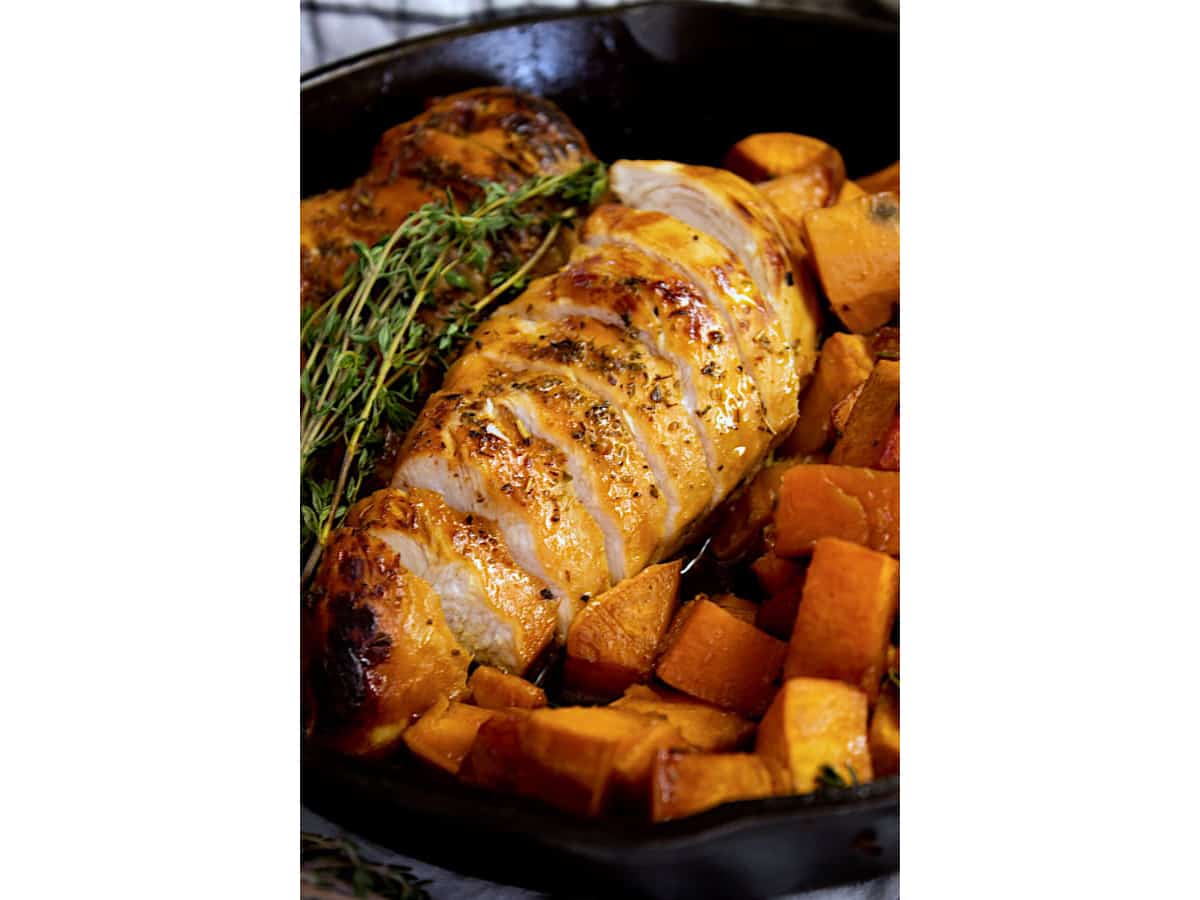 Perfectly cooked chicken on a plate surrounded by cubed sweet potatoes.