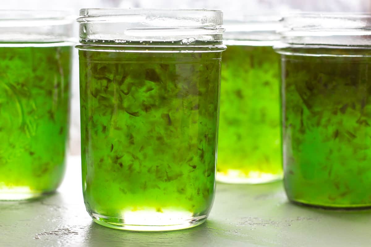 Side view of green jelly jars lined up.