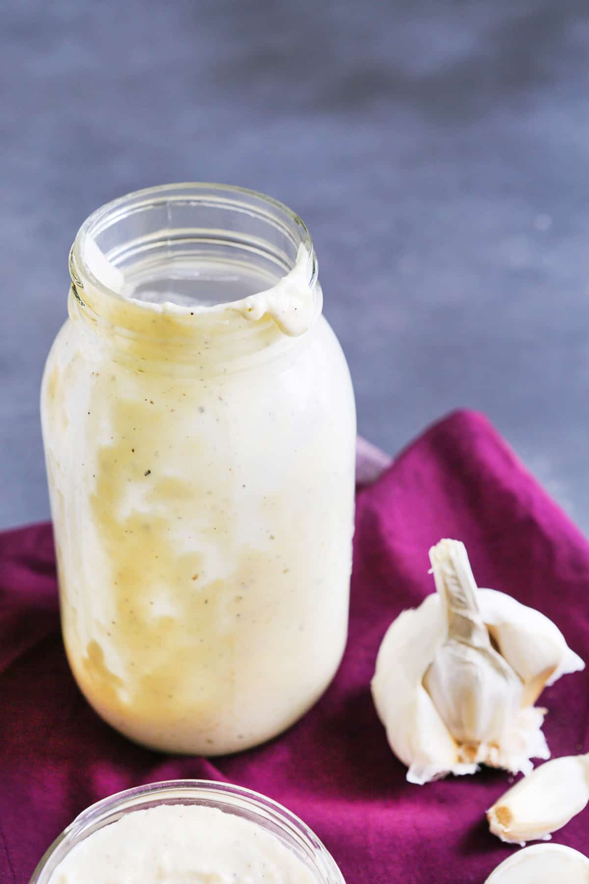 Large mason jar with alfredo sauce inside and dripping down sides.