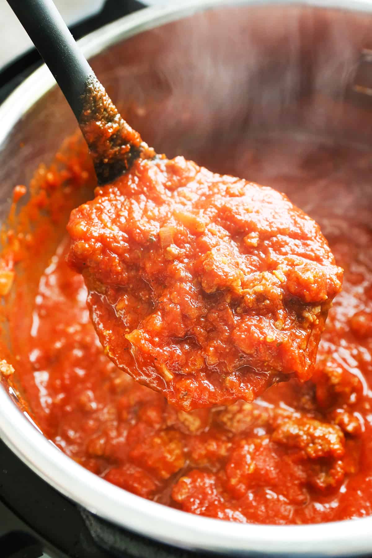Ladle filled with a thick and chunky spaghetti sauce.