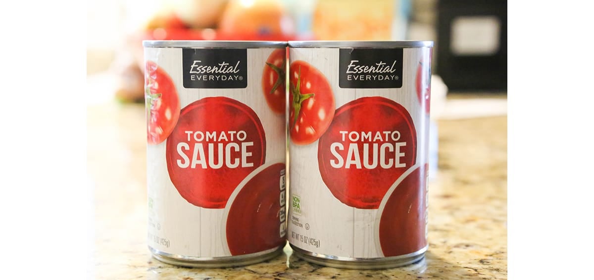 Two cans of tomato sauce lined up on a counter.