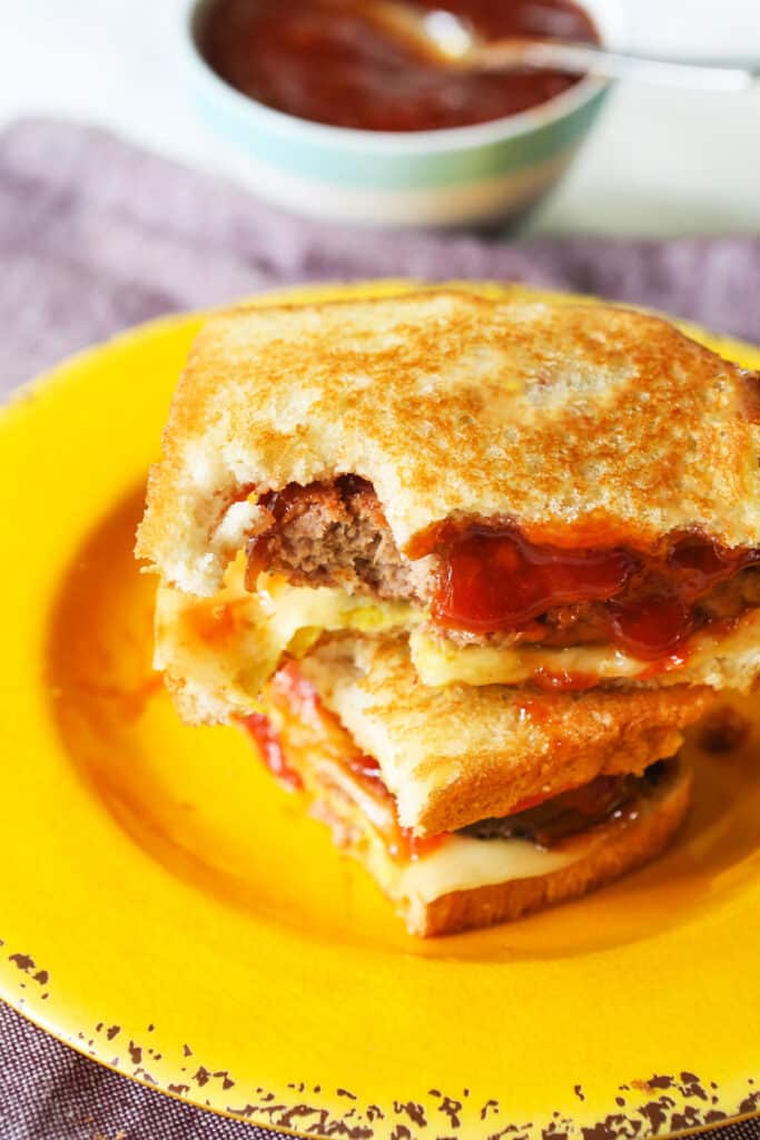 Two halves of a meatloaf sandwich stacked on a plate. 