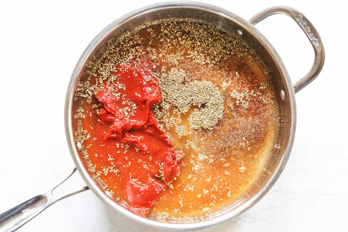 Tomato paste and spices in a skillet, ready to cook.
