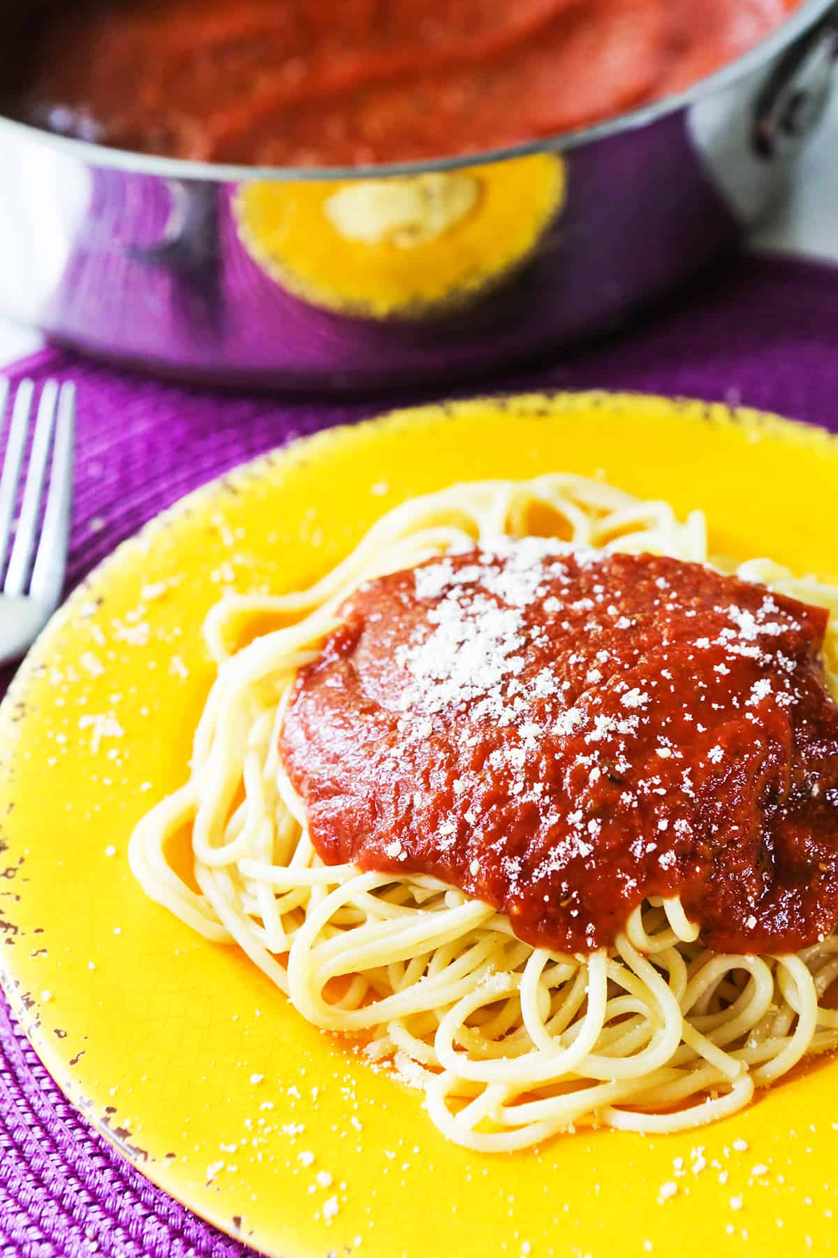 Plate of spaghetti with sauce and Parmesan cheese sprinkled on top.