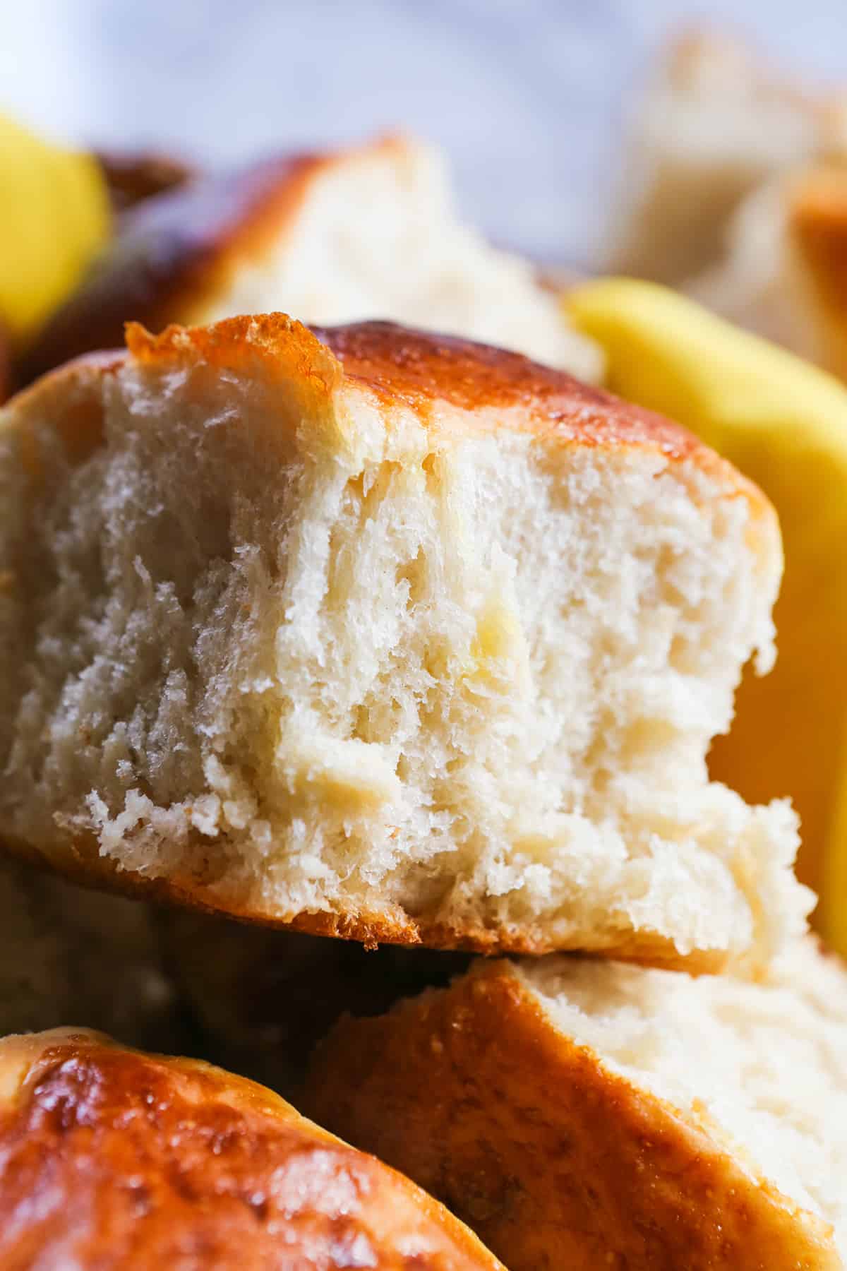 Fluffy dinner roll sitting on top of a huge stack of them.