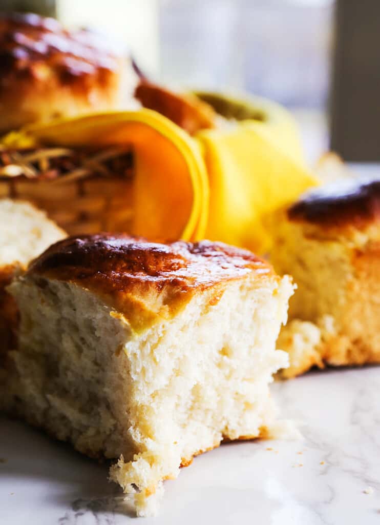 Dinner Rolls sitting in front of a basket of more rolls. 