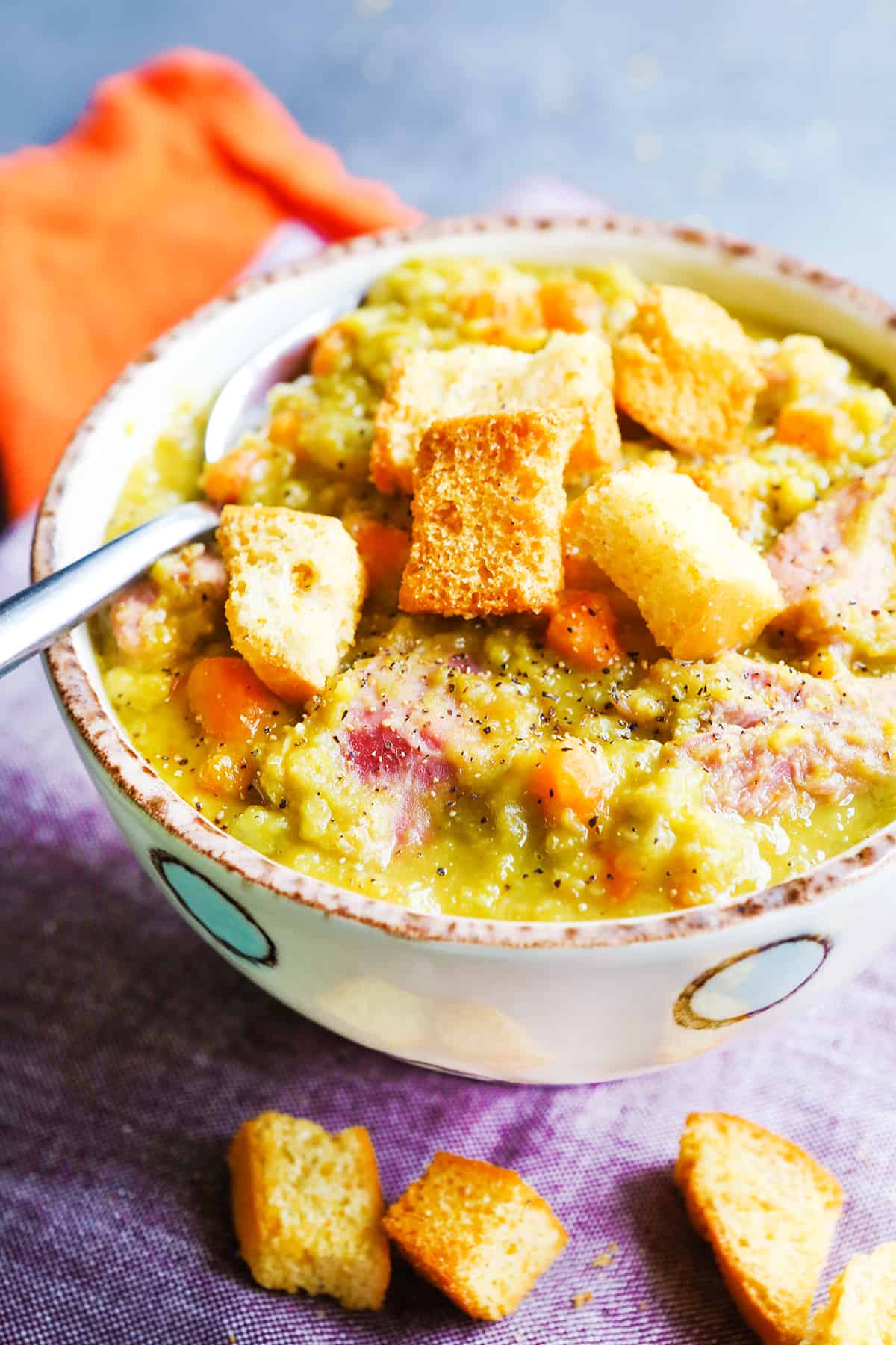 Bowl of ham and split pea soup with croutons on top.