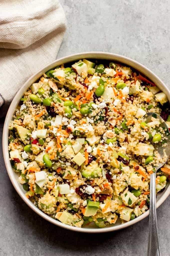 Quinoa apple salad in a serving bowl and a spoon tucked in. 