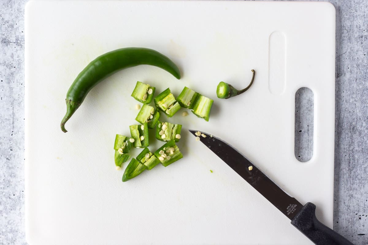 Green hot pepper chopped into chunks on a cutting board.
