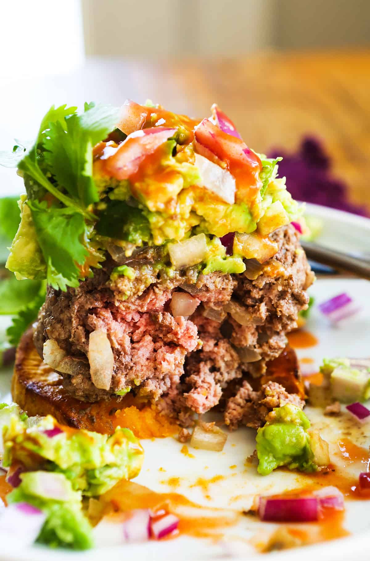 Center of a burger exposed and topped with guacamole.