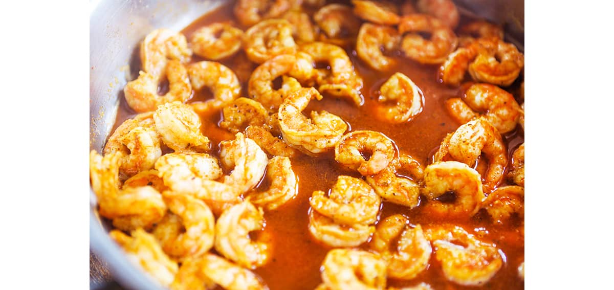 Cooked shrimp in a pan swimming in sauce.