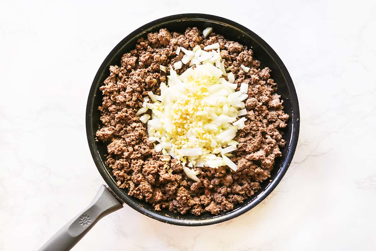 Top view of a skillet filled with cooked ground beef and onions.