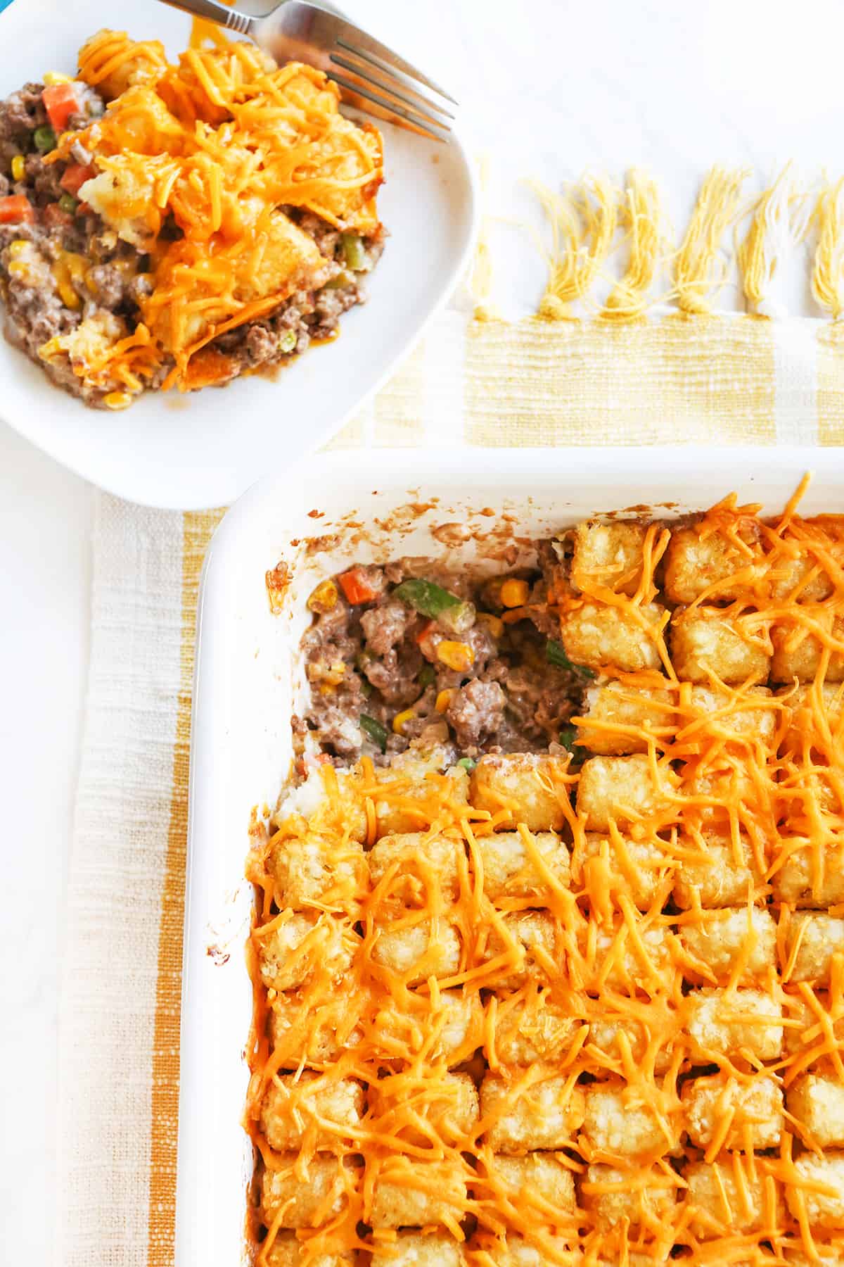 Tater tot casserole in a baking dish with a serving removed.