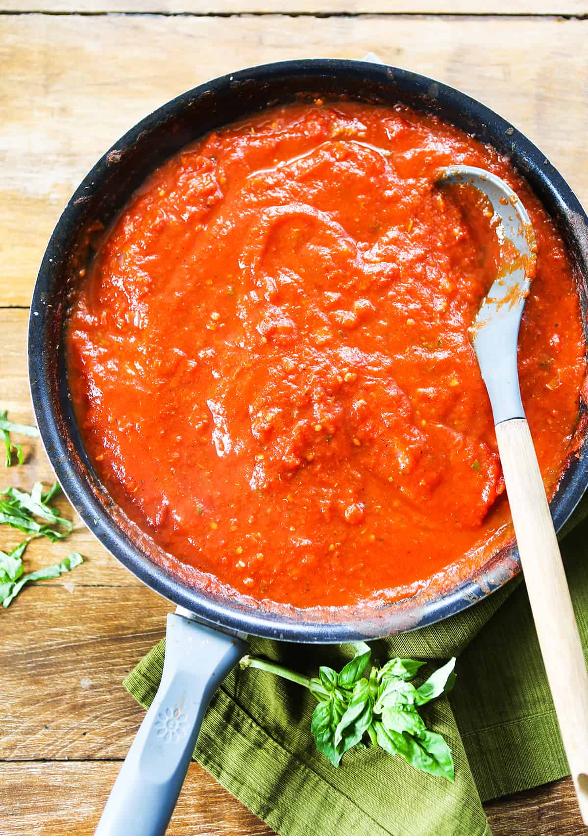 Top view of a skillet filled with marinara sauce and a serving spoon stick into the mixture.